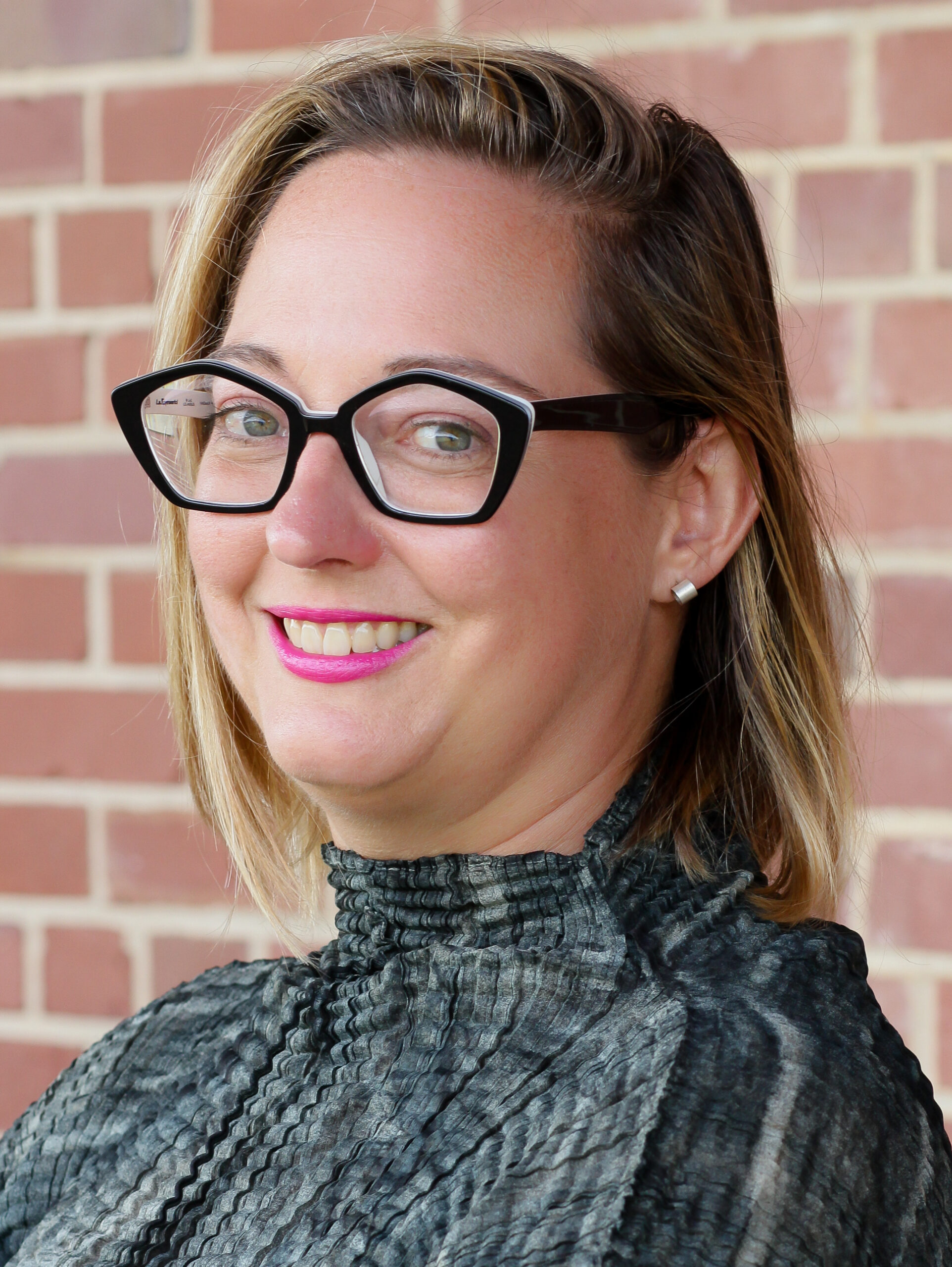 Jen Sudul Edwards standing in front of a brick wall