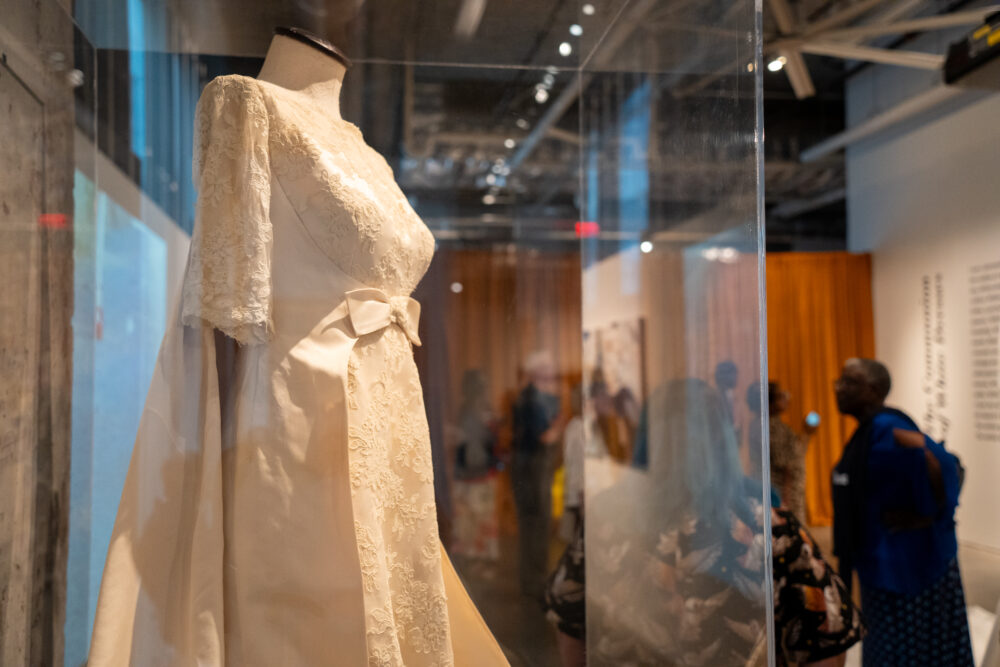 White dress inside vitrine with people walking in background