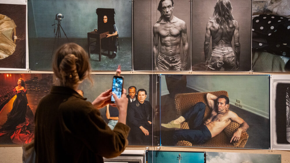 Person taking photo in Annie Leibovitz exhibition on gallery wall