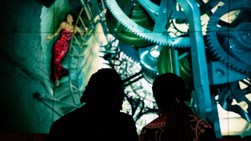 Two people watching digital screens in Annie Leibovitz exhibition