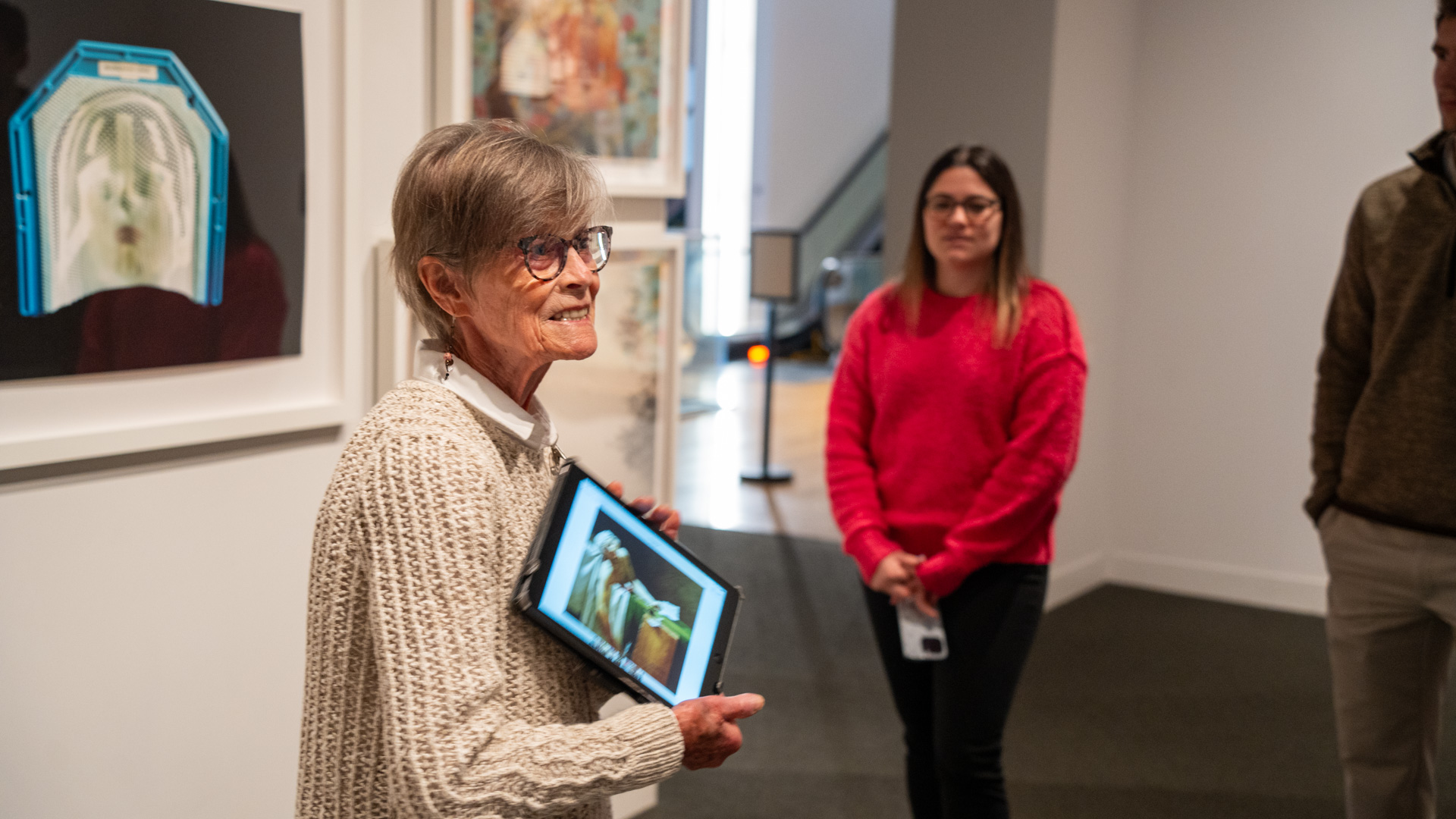 Docent holding ipad and speaking to group of people in the gallery