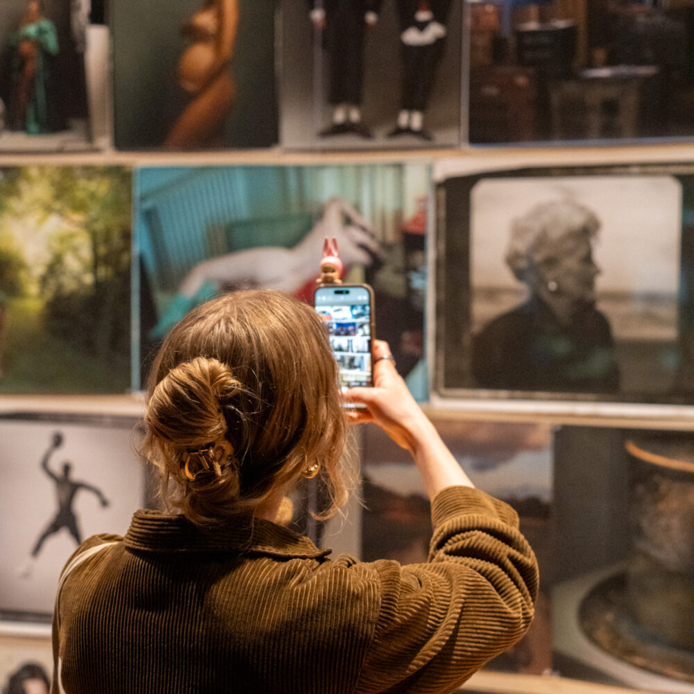 person holding phone up to take photos in Annie Leibovitz exhibition